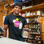 Ron's Bowling Alley employee handing a pair of bowling shoes over the counter.