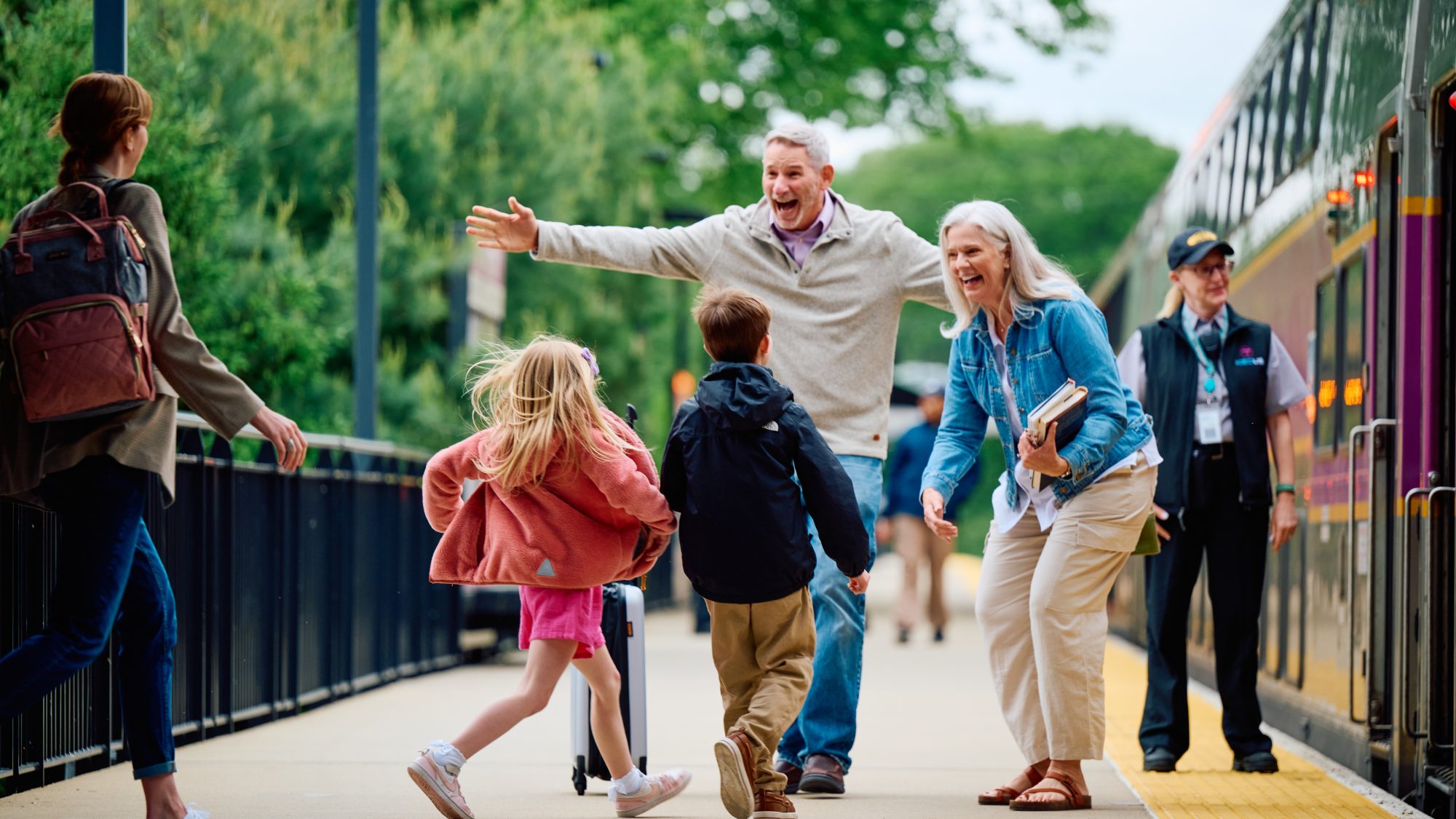 Children running up to grandparents to greet them on train station platform
