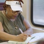 Woman writing in a notebook on a Commuter Rail train.