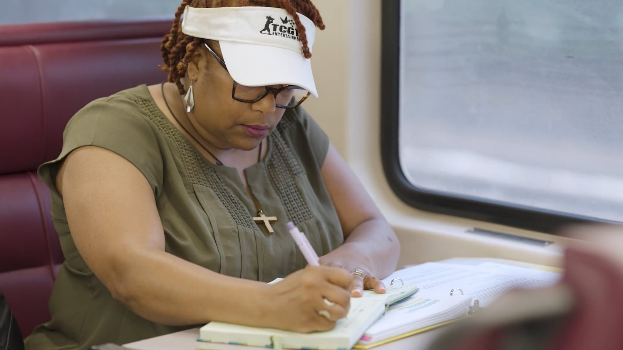 Woman writing in a notebook on a Commuter Rail train.