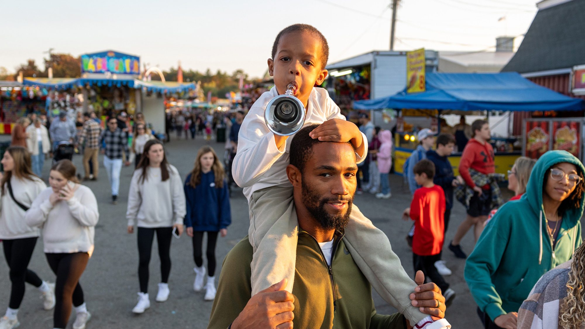 Father carrying son on his shoulders at a fall fair